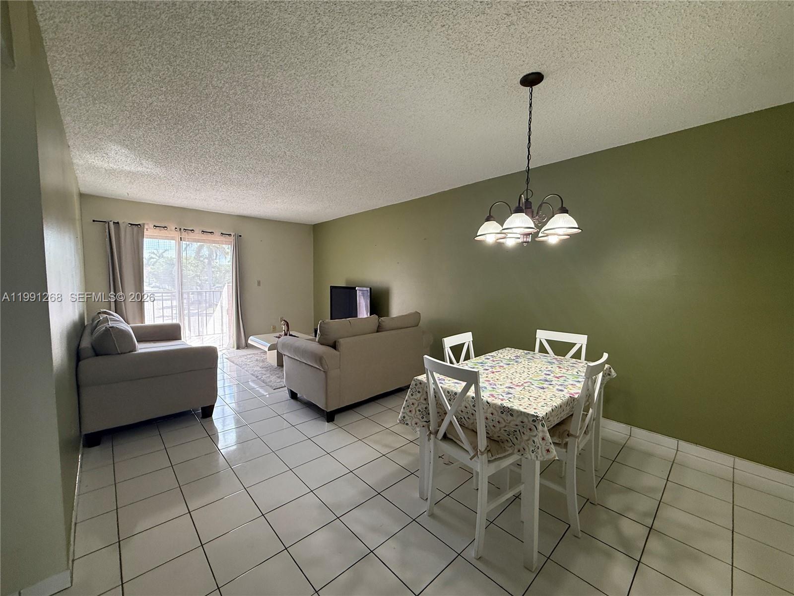 A living and dining area features white tile floors, an olive green wall, and furniture — 1800 W 54th St # 108, Hialeah FL 33012, HIALEAH, FL