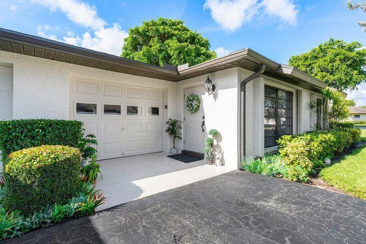 A white house exterior features a garage, a front door with a wreath, and landscaping — 4948 Equestrian Circle # B, Boynton Beach FL 33436, BOYNTON BEACH, FL