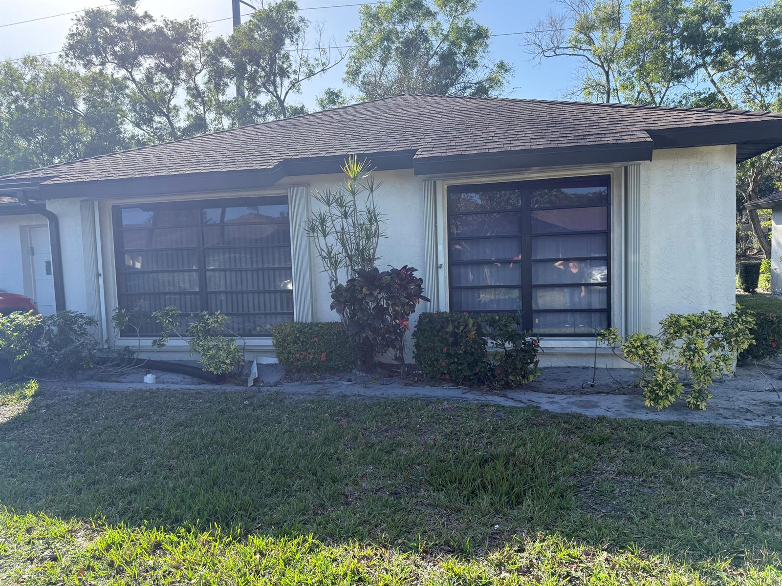 The exterior of a single-story house features a stucco facade, dark roof, and two large windows — 4948 Equestrian Circle # B, Boynton Beach FL 33436, BOYNTON BEACH, FL