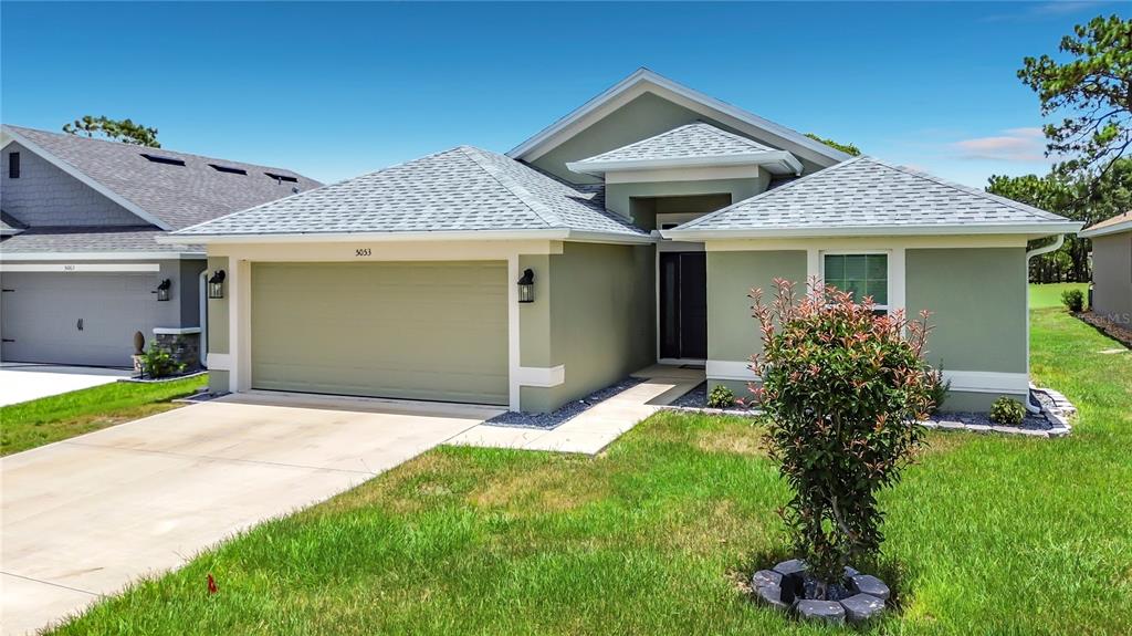 A single-story house with a green stucco exterior, a two-car garage, and a shingled roof — 5053 N TRIPLE EAGLE PATH, BEVERLY HILLS, FL