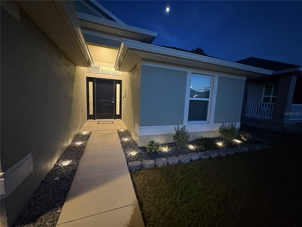 A concrete walkway leads to the front entrance of a house at night — 5053 N TRIPLE EAGLE PATH, BEVERLY HILLS, FL
