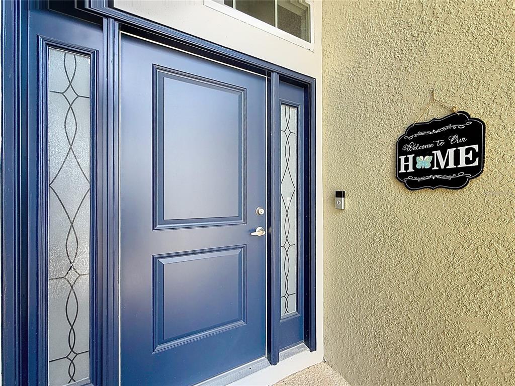 A blue front door with glass sidelights and a decorative welcome sign on the wall — 5053 N TRIPLE EAGLE PATH, BEVERLY HILLS, FL