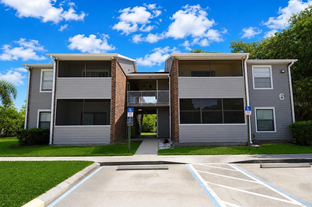 A two-story apartment building with gray siding, brick accents, and a central breezeway — 1400 GANDY BOULEVARD N UNIT 607, ST PETERSBURG, FL