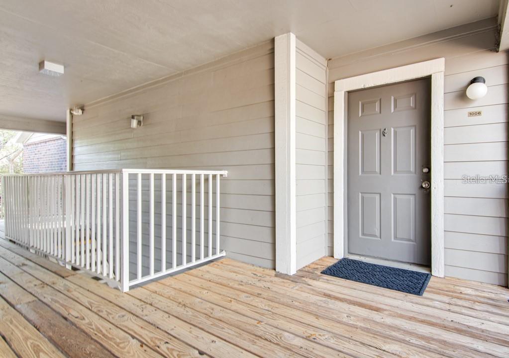 A gray front door with a white trim sits on a wooden porch with railings — 1400 GANDY BOULEVARD N UNIT 607, ST PETERSBURG, FL