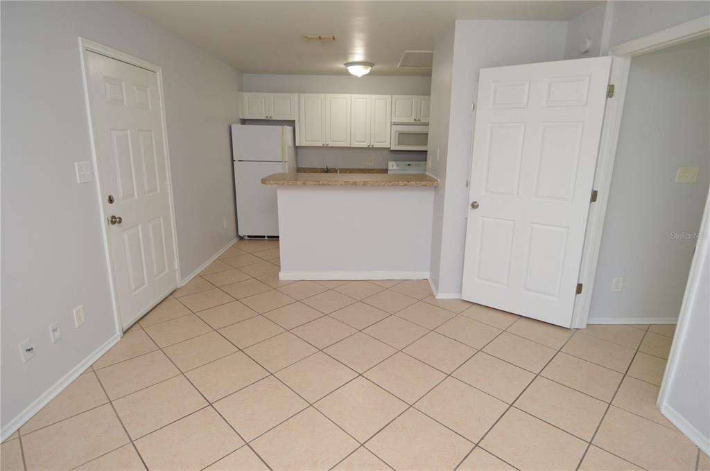 This kitchen features white cabinets, a breakfast bar, and light-colored tile flooring — 1400 GANDY BOULEVARD N UNIT 607, ST PETERSBURG, FL