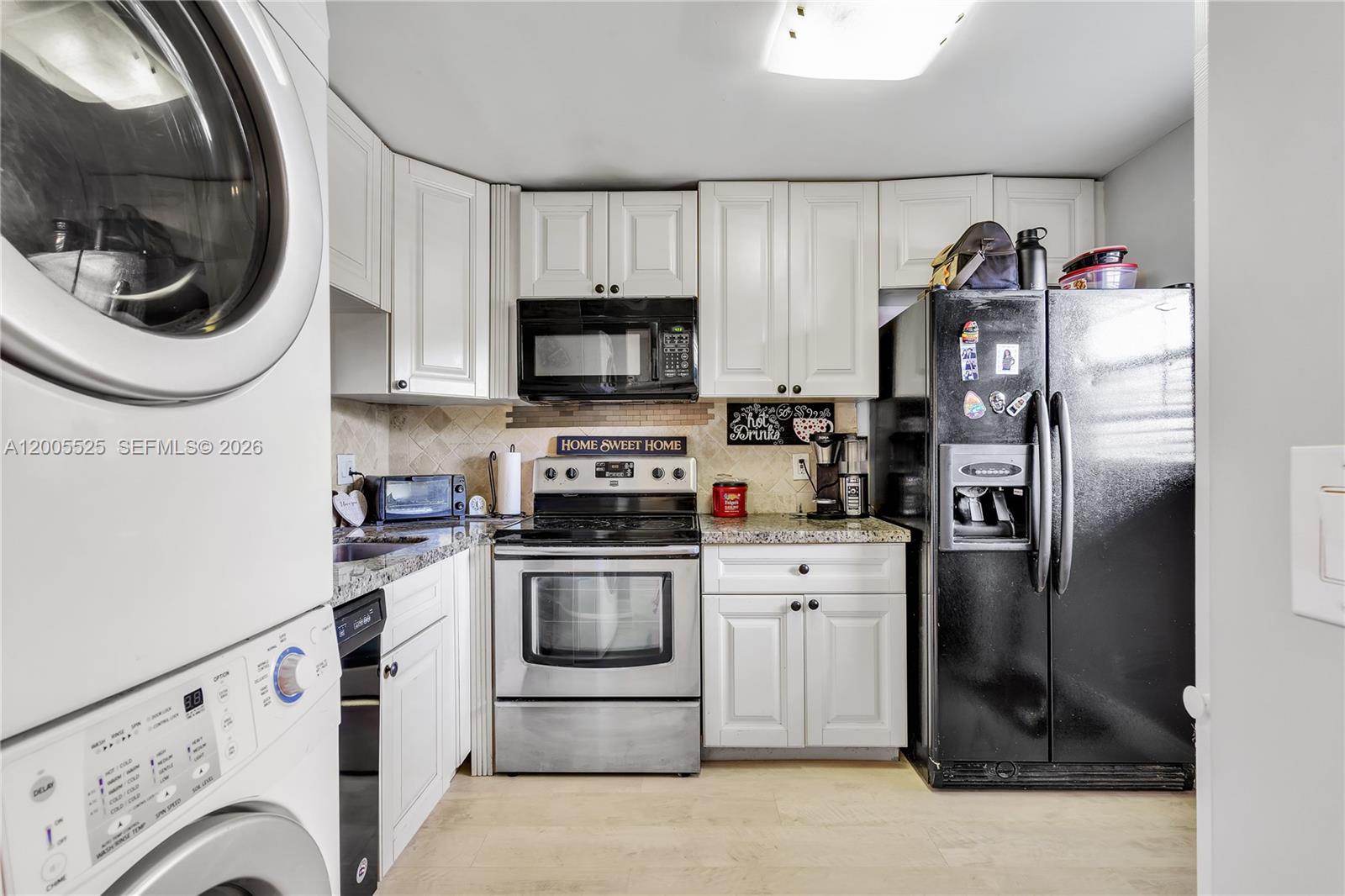 A kitchen features white cabinets, stainless steel appliances, a black refrigerator, and light wood flooring — 3777 NW 78th Ave # 15A, Davie FL 33024, DAVIE, FL