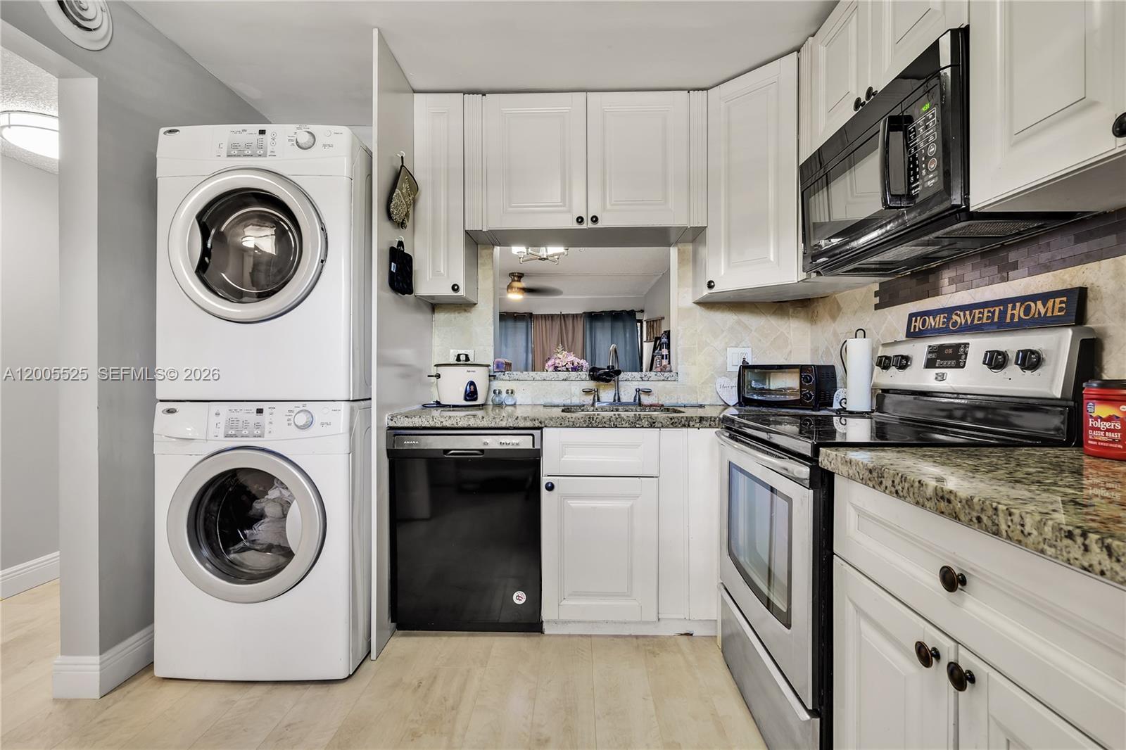 A kitchen features white cabinets, granite countertops, stainless steel appliances, and a stacked laundry unit — 3777 NW 78th Ave # 15A, Davie FL 33024, DAVIE, FL