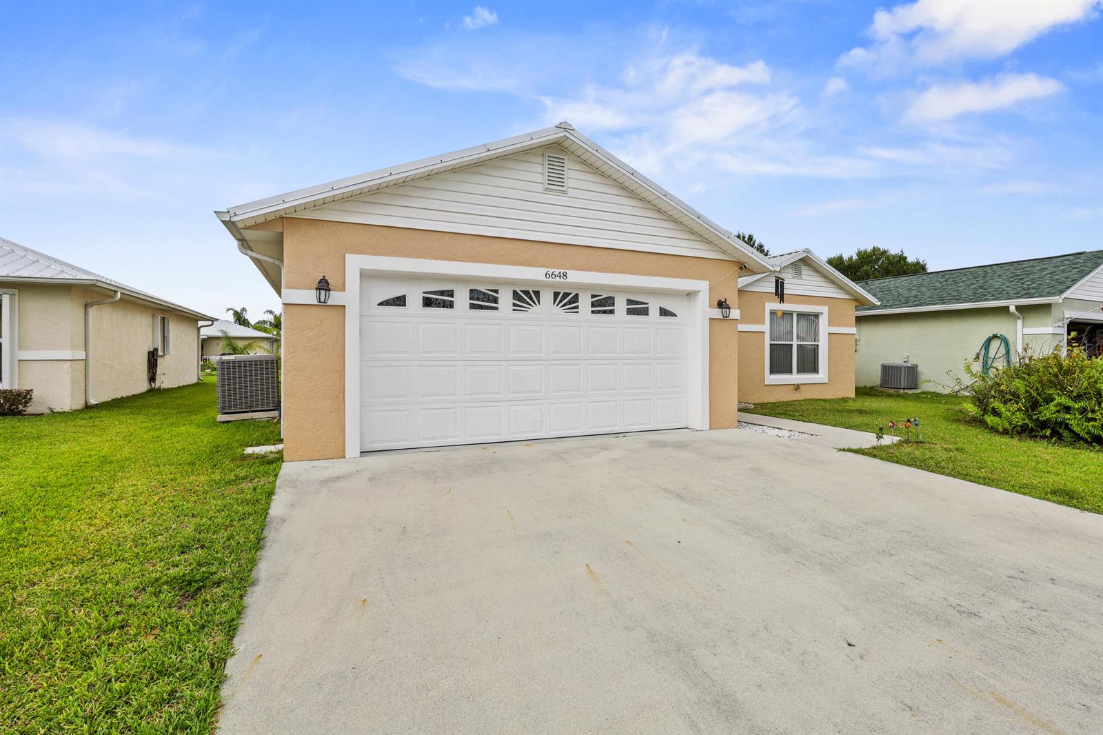 A tan single-story house features a two-car garage, white trim, and a concrete driveway — 6648 Gaviota, Fort Pierce FL 34951, FORT PIERCE, FL