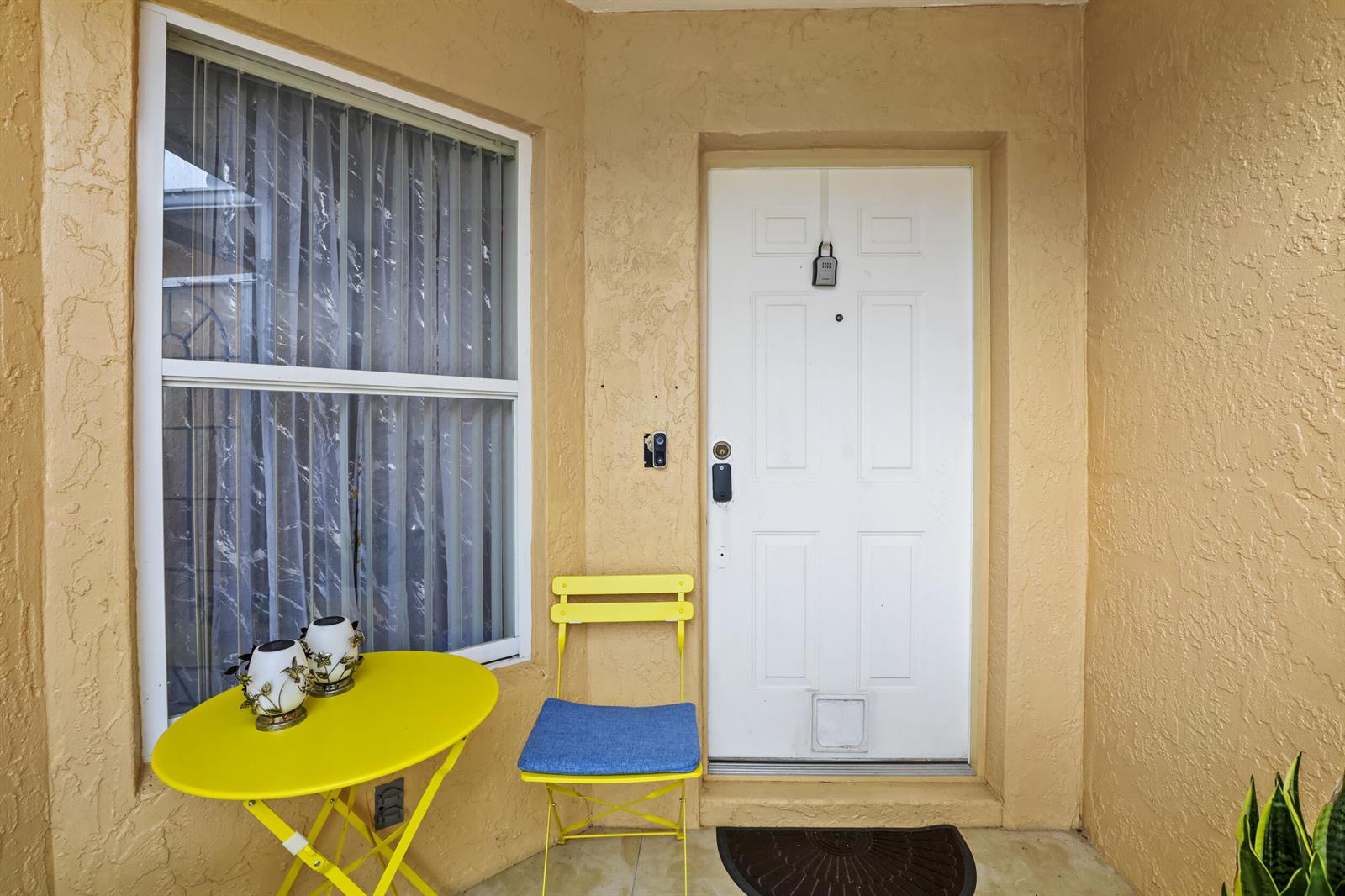 A yellow metal bistro set sits on a porch next to a white front door — 6648 Gaviota, Fort Pierce FL 34951, FORT PIERCE, FL