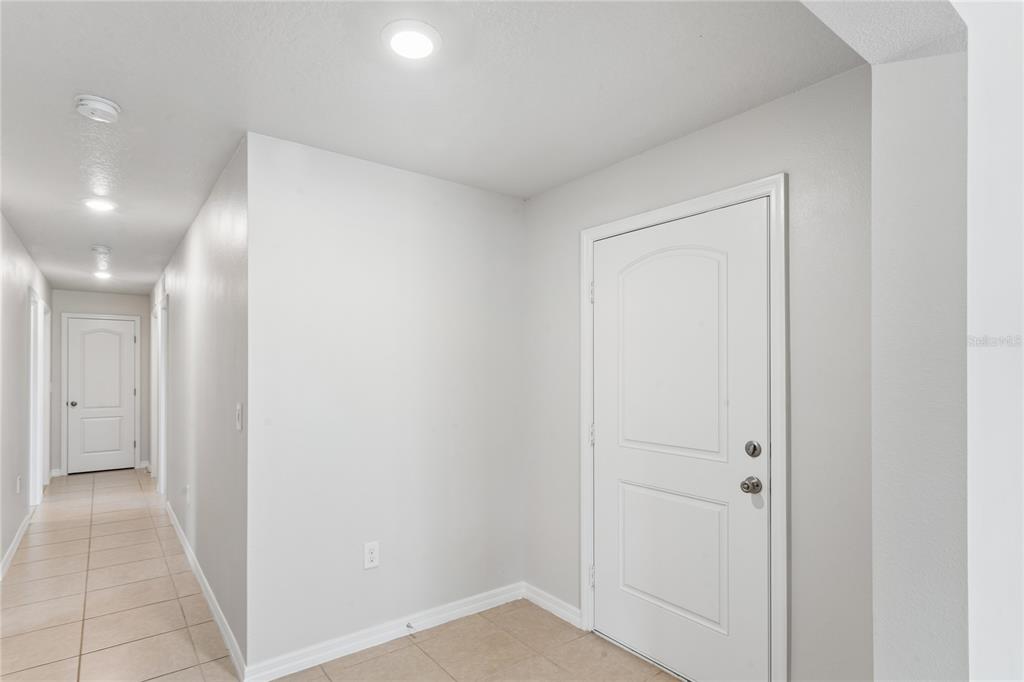 A bright entryway features light-colored tile flooring, white walls, and a white interior door — 2403 CASPIAN DRIVE, LAKELAND, FL