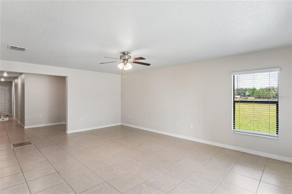 An empty living room with light tile flooring, a ceiling fan, and a single window — 2403 CASPIAN DRIVE, LAKELAND, FL