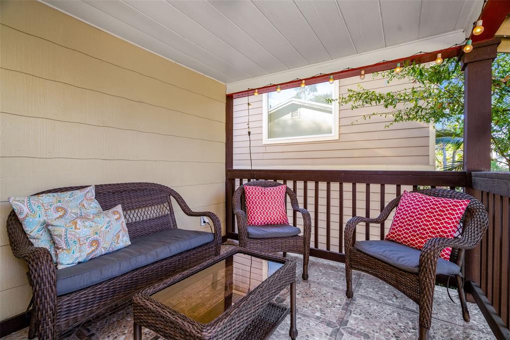 A covered outdoor patio features wicker furniture, a glass-top table, and string lights — 826 11TH AVENUE S Apt 1, ST PETERSBURG, FL