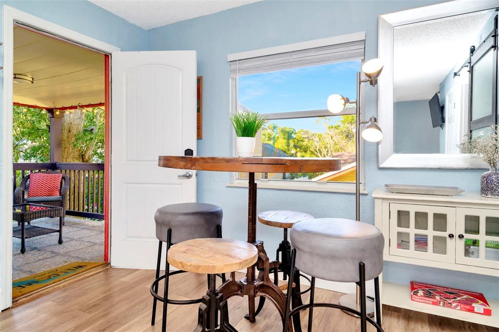 A dining area with a round wooden table, stools, and a doorway leading to a porch — 826 11TH AVENUE S Apt 1, ST PETERSBURG, FL