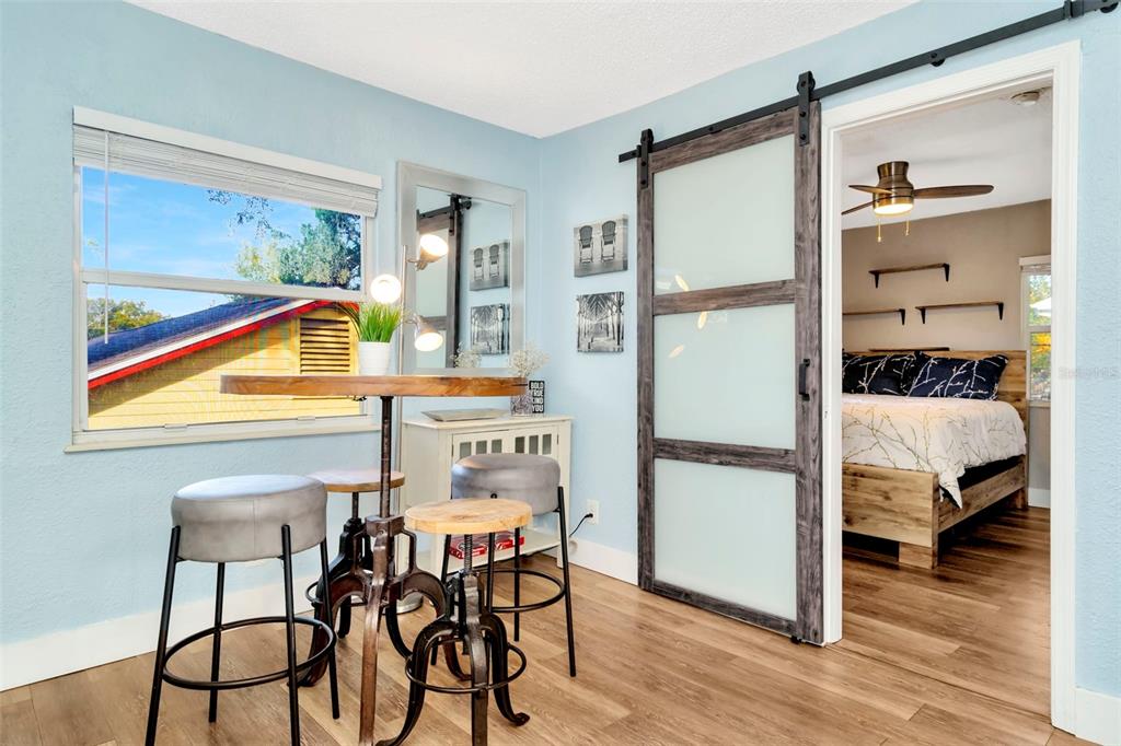 A dining area with a high table and stools sits beside a sliding frosted glass door — 826 11TH AVENUE S Apt 1, ST PETERSBURG, FL