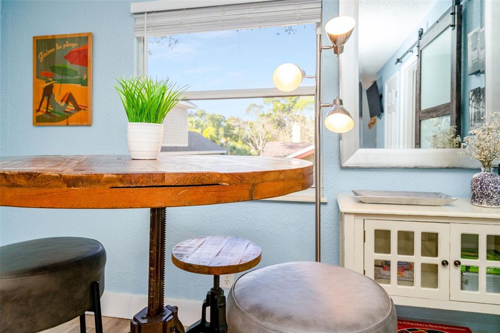 A round wooden table with stools sits in a light blue room by a window — 826 11TH AVENUE S Apt 1, ST PETERSBURG, FL