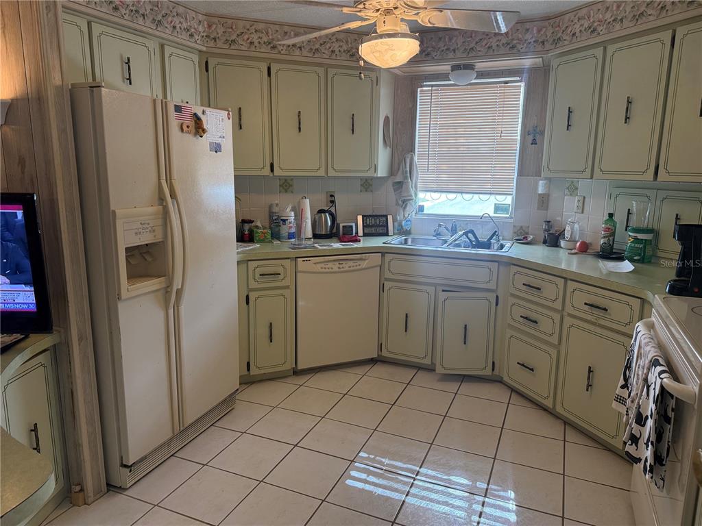A kitchen with light green cabinets, white appliances, tiled flooring, and a window above the sink — 5640 FORSYTHIA ROAD, VENICE, FL