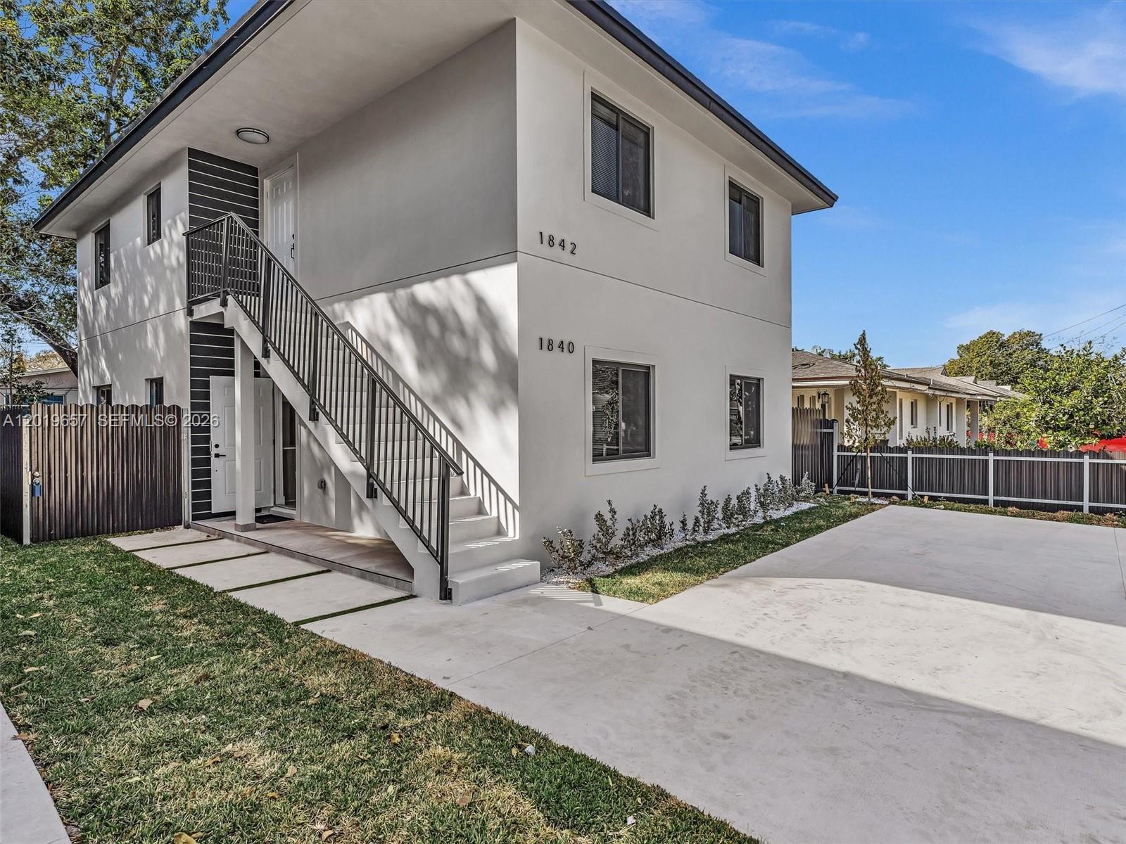 A two-story white building features an exterior staircase and a concrete driveway — 1840 NW 63rd St, Miami FL 33147, MIAMI, FL