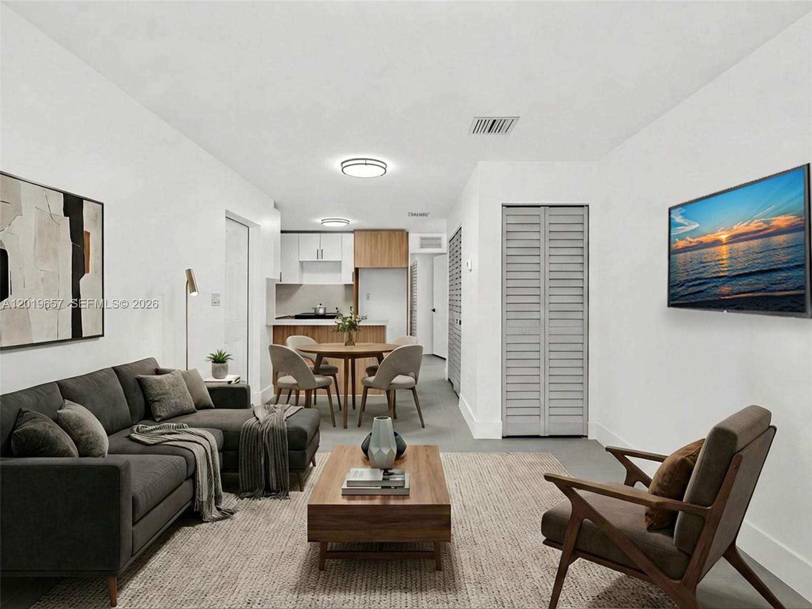 This living room features a gray sectional sofa, a wooden coffee table, and an adjacent kitchen — 1840 NW 63rd St, Miami FL 33147, MIAMI, FL