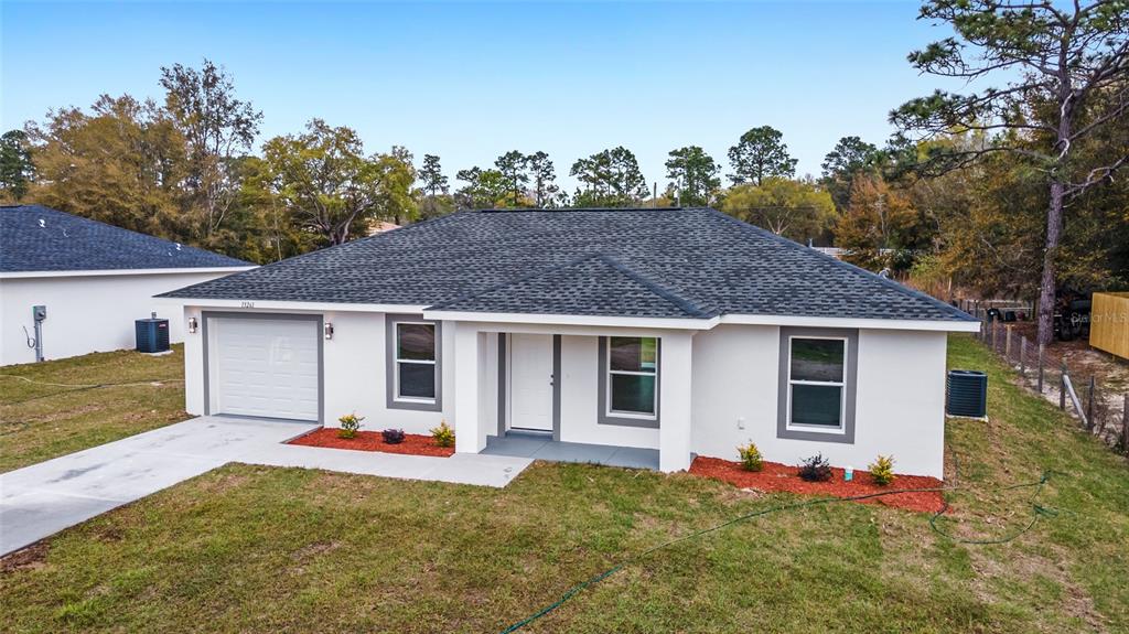 A single-story white house with a dark shingled roof and a one-car garage — 146 SW TREE TOP ROAD, DUNNELLON, FL