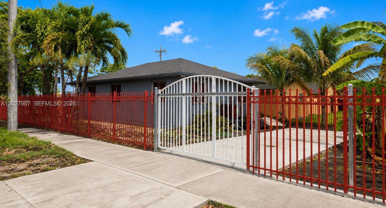 A gray house sits behind a red metal fence with a white gate — 4952 NW 21st Ave # 0, Miami FL 33142, MIAMI, FL
