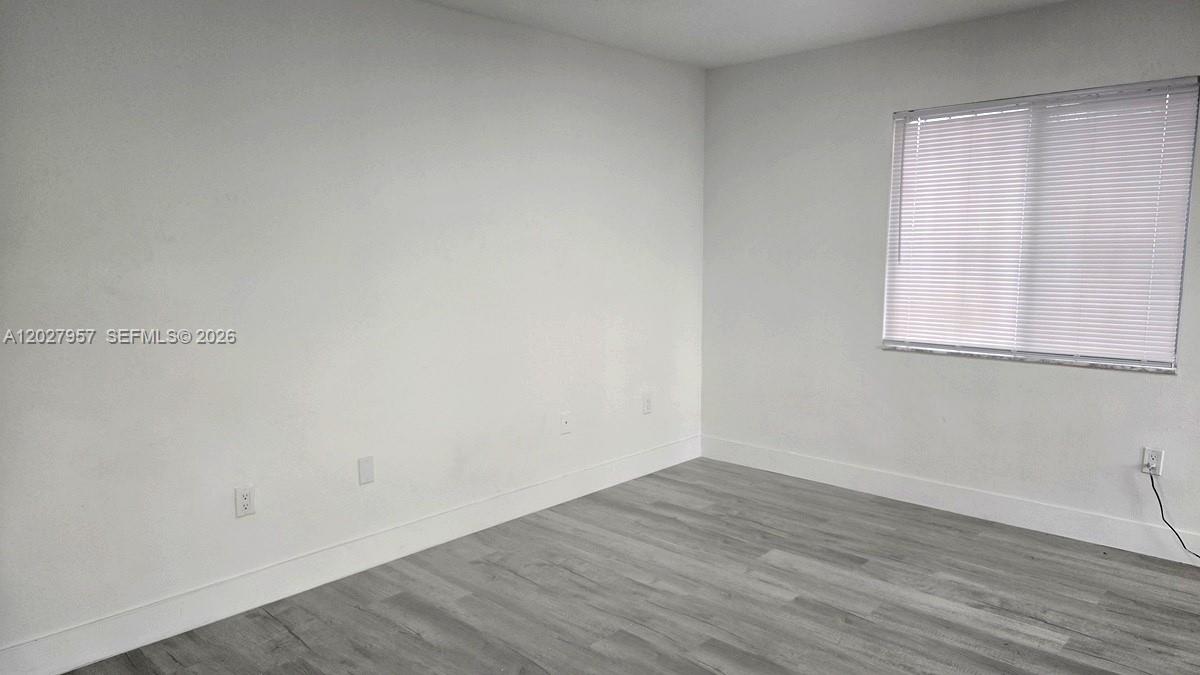 An empty room features white walls, light gray wood-look flooring, and a window with blinds — 4952 NW 21st Ave # 0, Miami FL 33142, MIAMI, FL