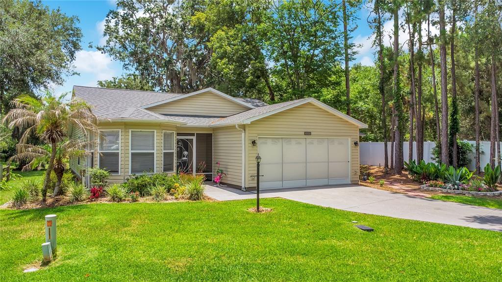 A single-story tan house with a two-car garage and a front lawn with trees — 32222 SUMMERTREE CIRCLE, LEESBURG, FL