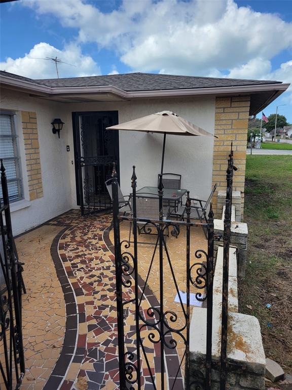 A patio with a mosaic tile floor, wrought iron gate, and outdoor dining set — 7530 JUDITH CRESCENT CRESCENT, PORT RICHEY, FL
