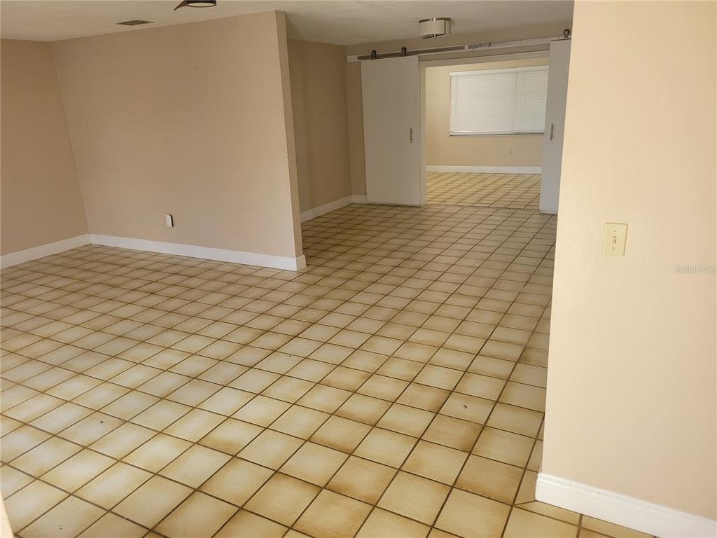 An interior view shows a tiled room leading through sliding barn doors to another space — 7530 JUDITH CRESCENT CRESCENT, PORT RICHEY, FL