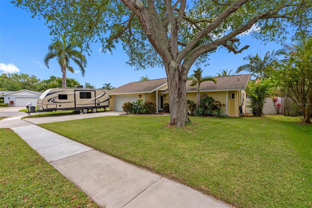 A yellow single-story house with a large tree and a parked RV in the driveway — 13440 RUSTIC PINES BOULEVARD S, SEMINOLE, FL