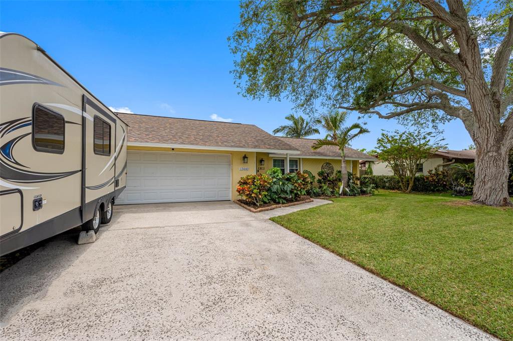 A single-story house with a beige exterior, a two-car garage, and a parked recreational vehicle — 13440 RUSTIC PINES BOULEVARD S, SEMINOLE, FL