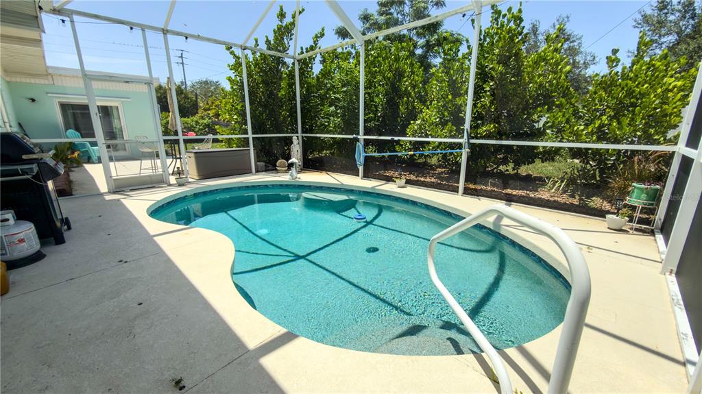 A screened-in patio features a kidney-shaped swimming pool with a white metal handrail — 2215 ALVARADO LANE, SARASOTA, FL