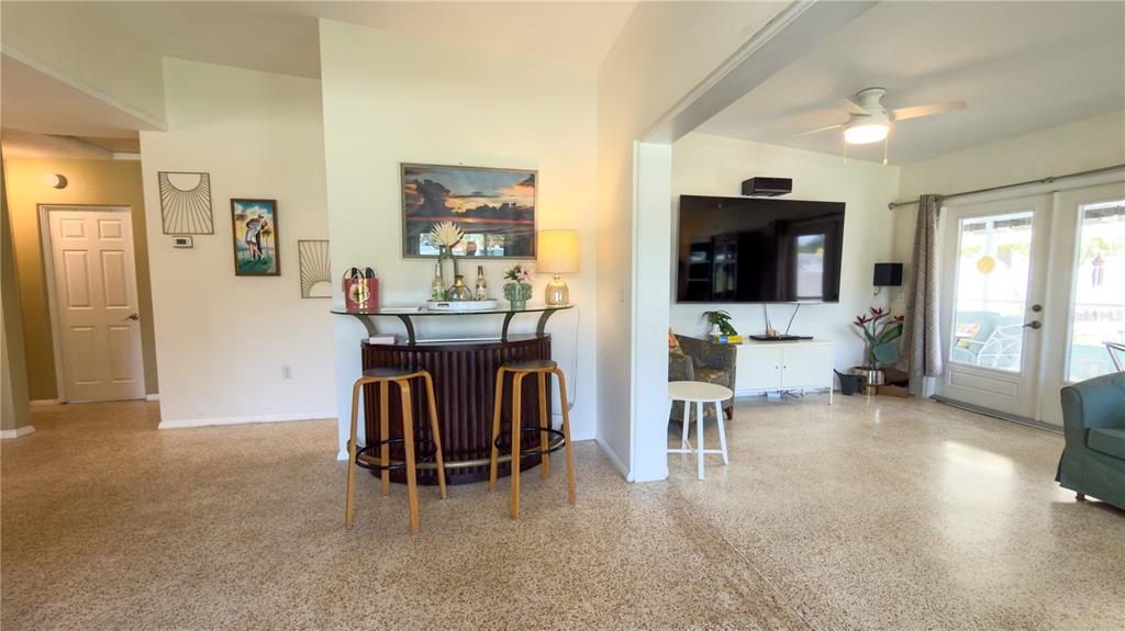 A living room features a curved home bar, terrazzo flooring, and a large wall-mounted television — 2215 ALVARADO LANE, SARASOTA, FL