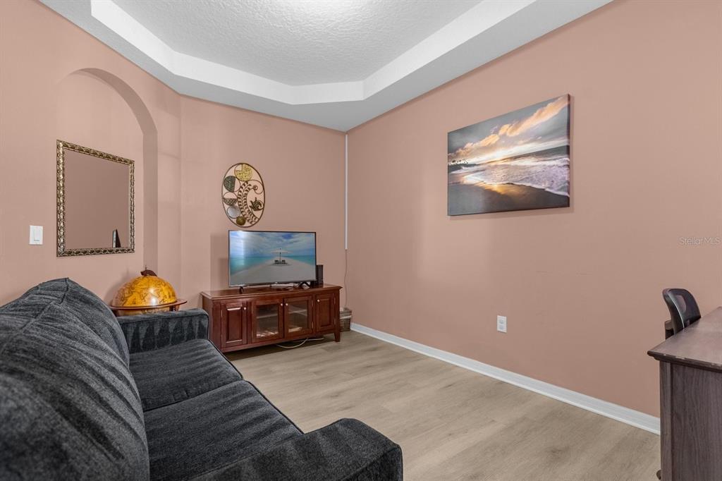 A living room features a dark sofa, a television on a wooden stand, and peach walls — 315 CHEROKEE AVENUE, HAINES CITY, FL