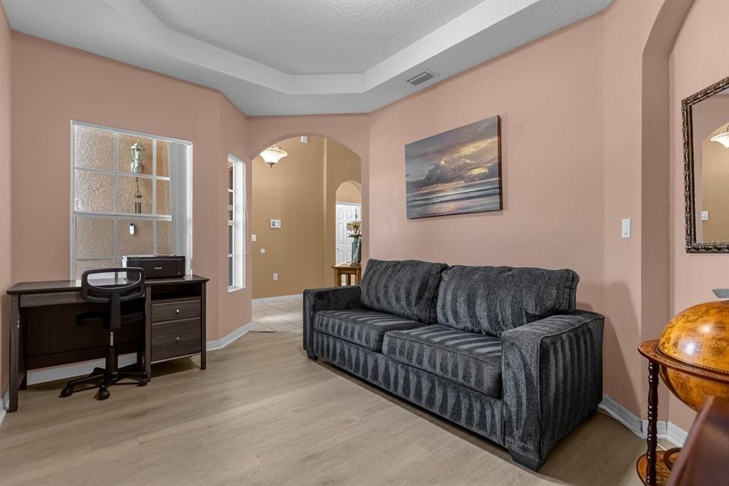 A room with light wood floors, peach walls, a dark sofa, and a desk — 315 CHEROKEE AVENUE, HAINES CITY, FL