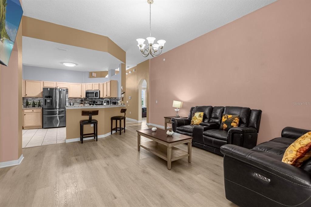 A living room with light wood flooring, leather sofas, and an open kitchen with bar seating — 315 CHEROKEE AVENUE, HAINES CITY, FL