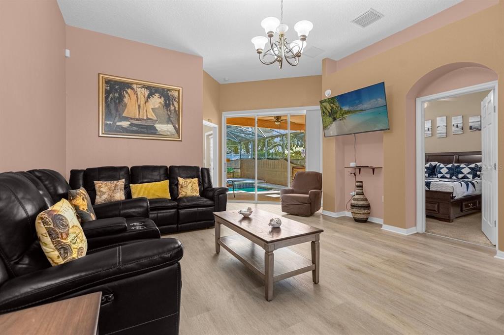 A living room with black leather sofas, a wooden coffee table, and a pool view — 315 CHEROKEE AVENUE, HAINES CITY, FL