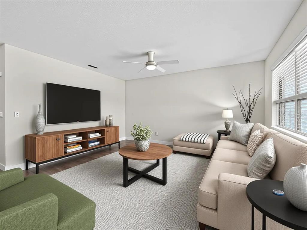 A living room features a television, wooden media console, round coffee table, and beige sofa — 16701 BROADFORD LANE, CLERMONT, FL