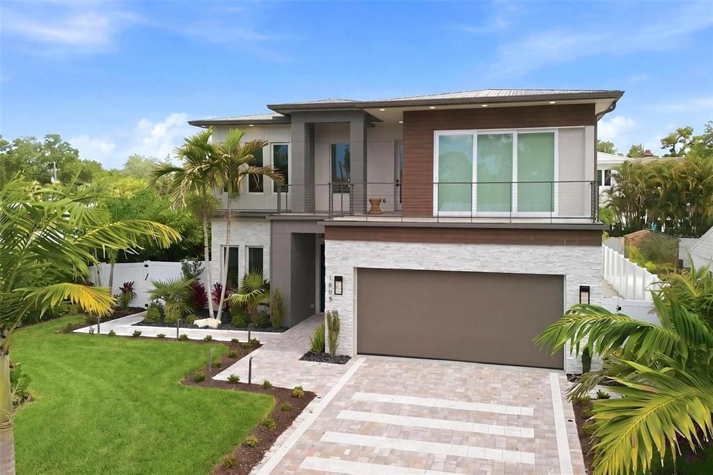 A modern two-story house with a stone facade, a balcony, and a paved driveway — 1805 GOLDENROD STREET, SARASOTA, FL