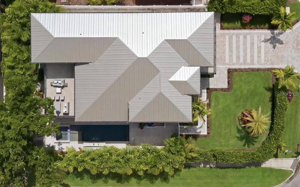 An aerial view shows a house with a metal roof, a pool, and landscaped grounds — 1805 GOLDENROD STREET, SARASOTA, FL