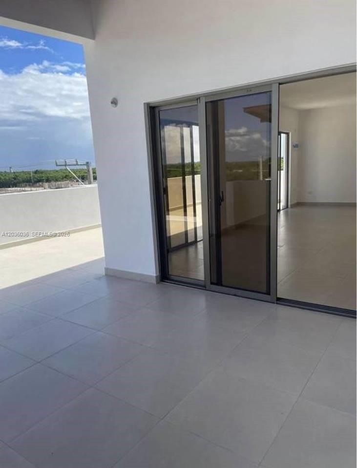 A covered balcony with light-colored tile flooring leads into an interior room through sliding doors — 0 Cap cana # 0, FL