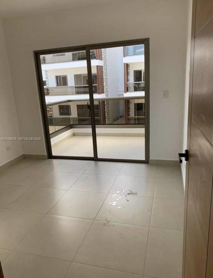An empty room with light-colored tile flooring features a sliding glass door leading to a balcony — 0 Cap cana # 0, FL