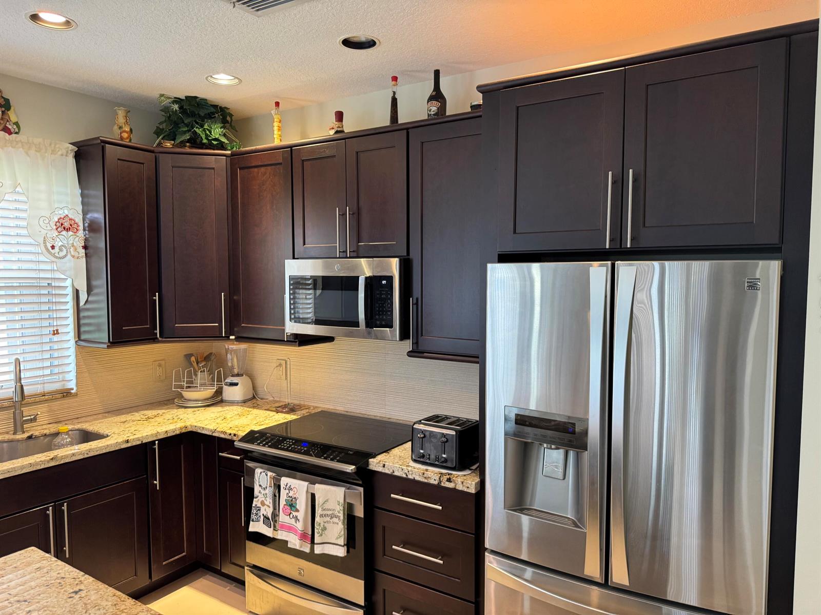 A kitchen features dark wood cabinets, stainless steel appliances, and granite countertops — 21196 Via Ventura # 21196, Boca Raton FL 33433, BOCA RATON, FL