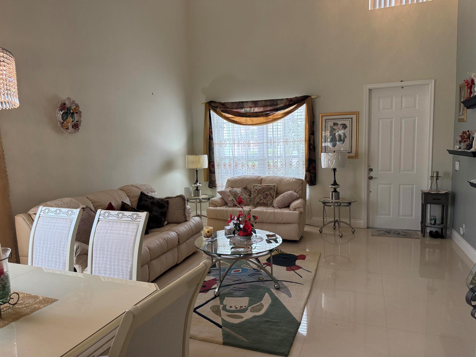 A living room features light-colored sofas, a glass coffee table, and tile flooring — 21196 Via Ventura # 21196, Boca Raton FL 33433, BOCA RATON, FL