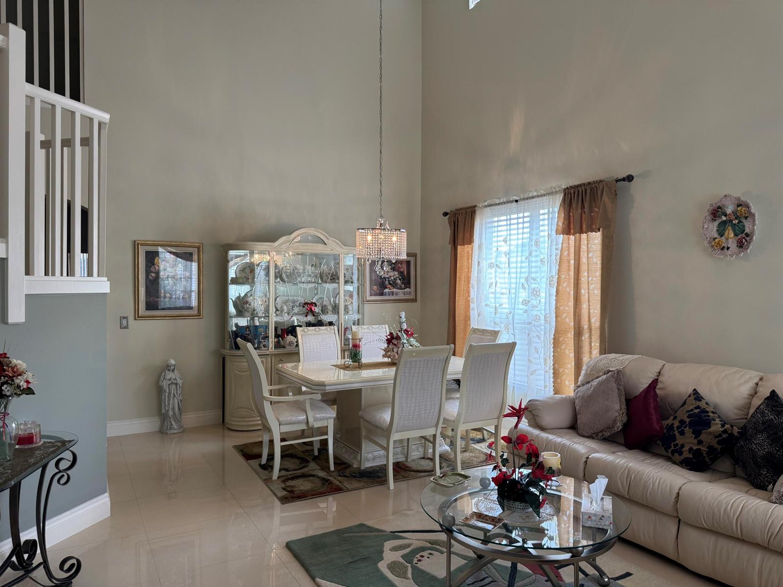 A dining area and living room with high ceilings, tile floors, and a crystal chandelier — 21196 Via Ventura # 21196, Boca Raton FL 33433, BOCA RATON, FL