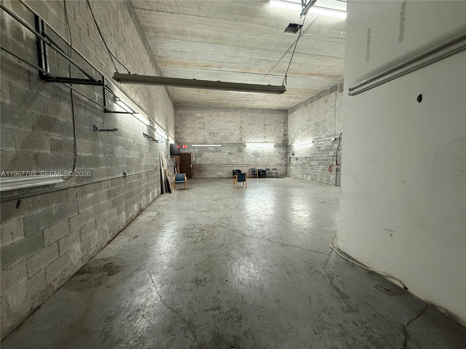 An empty industrial warehouse space features concrete block walls, a concrete floor, and overhead lighting — 13443 NW 47th Ave # 10, Opa-Locka FL 33054, OPA-LOCKA, FL