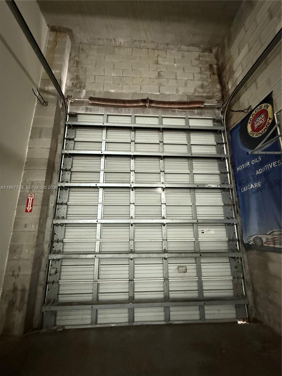 A tall metal roll-up garage door is installed in a room with concrete block walls — 13443 NW 47th Ave # 10, Opa-Locka FL 33054, OPA-LOCKA, FL