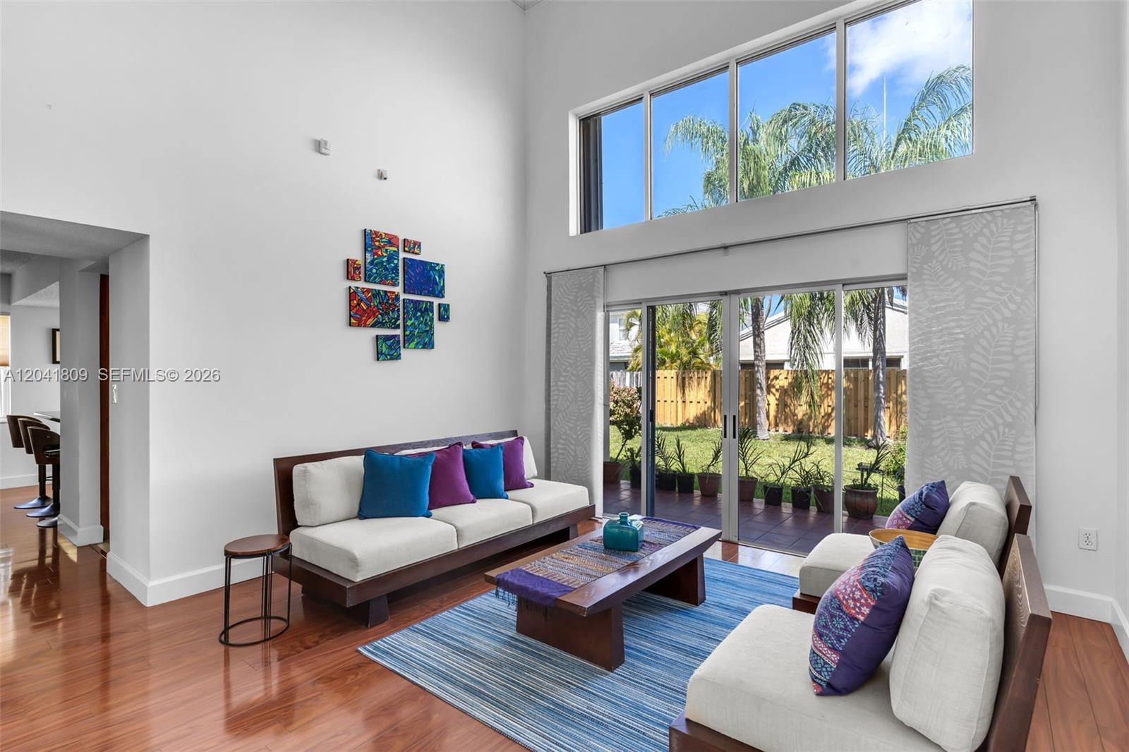 A living room features high ceilings, a large window, sliding glass doors, and modern furniture — 4766 SW 154th Ave, Miami FL 33185, MIAMI, FL