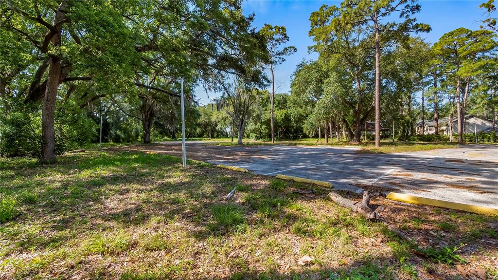 An outdoor parking lot is surrounded by mature trees and grassy areas — 1500 N HOAGLAND BOULEVARD, KISSIMMEE, FL