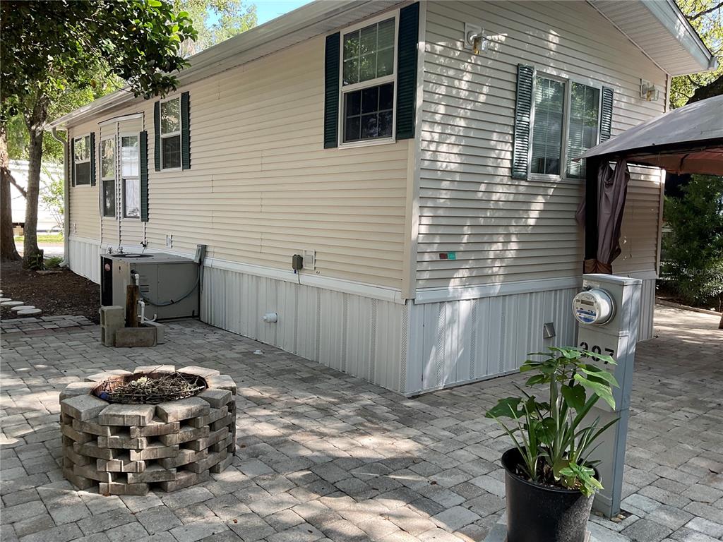 The exterior of a manufactured home features light siding, a paver patio, and a fire pit — 25378 140TH STREET NE, FORT MC COY, FL