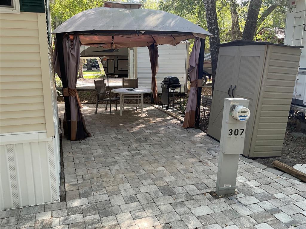 A paved patio features a gazebo, outdoor furniture, a grill, and a utility meter — 25378 140TH STREET NE, FORT MC COY, FL